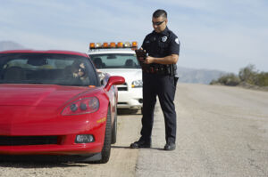 criminal defense attorney with a police office talking to a citizen in a red sports car during a traffic stop