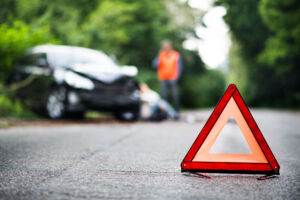 Car Accident Lawyer Lafayette, IN - A close up of a red emergency triangle on the road in front of a car after an accident.